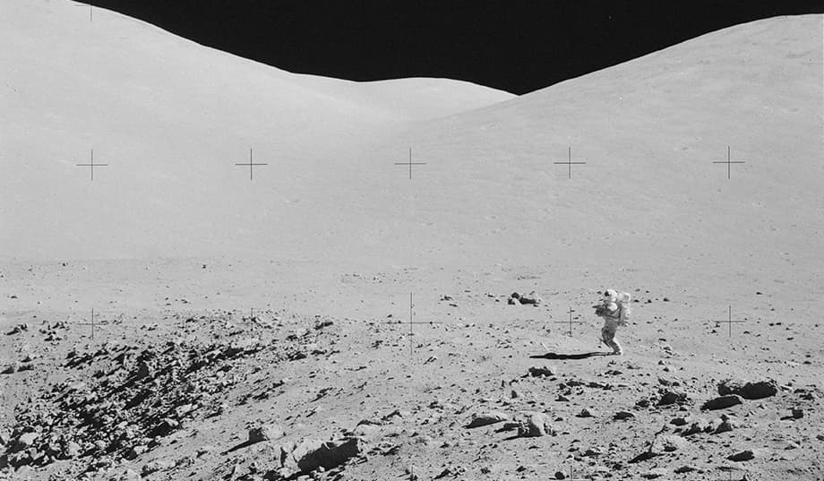 Eugene Cernan en la superficie de la Luna durante uno de los paseos espaciales de la misión. Está cerca del borde de un cráter y frente a unas colinas que se ven al fondo. Se le ve pequeño en el encuadre, lo que da una idea del aislamiento en el que estaban él y su compañero Harrison Schmitt