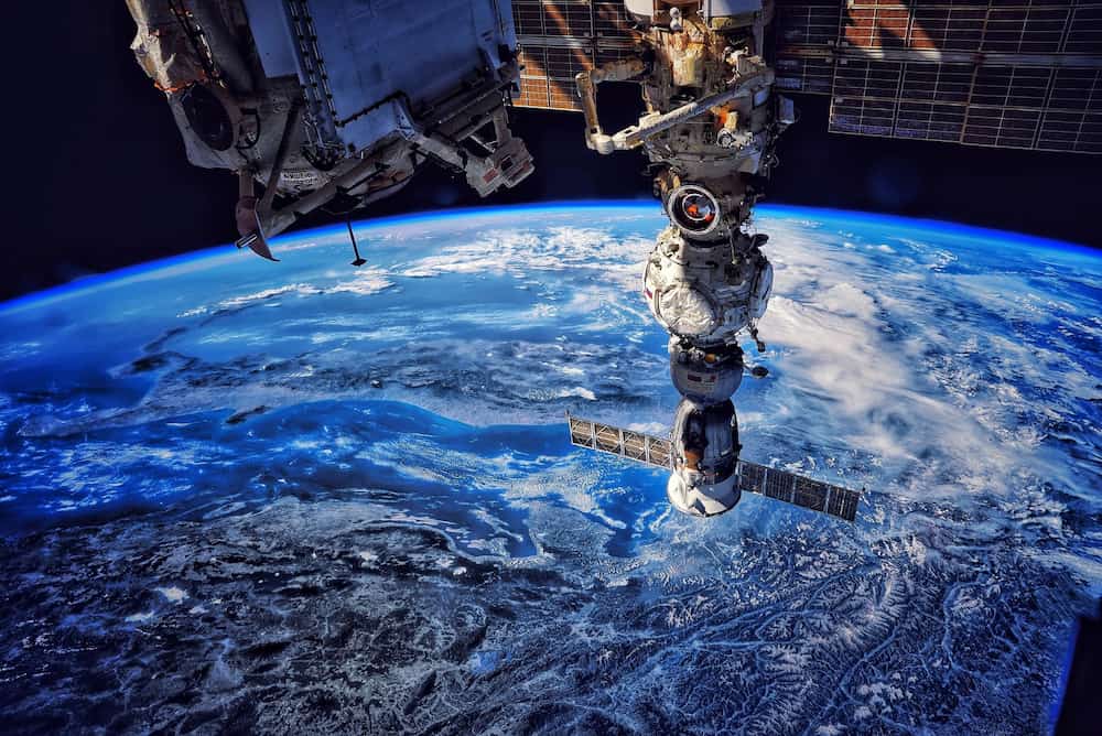 Foto de la EEI con la Tierra al fondo en la que se ven los módulos Nauka y Prichal con la Soyuz MS-21 acoplada a este; se ve también el Brazo robot europeo entre los paneles solares de Nauka, y en primer plano, parte del módulo Rassvet. En la Tierra, se reconoce Italia