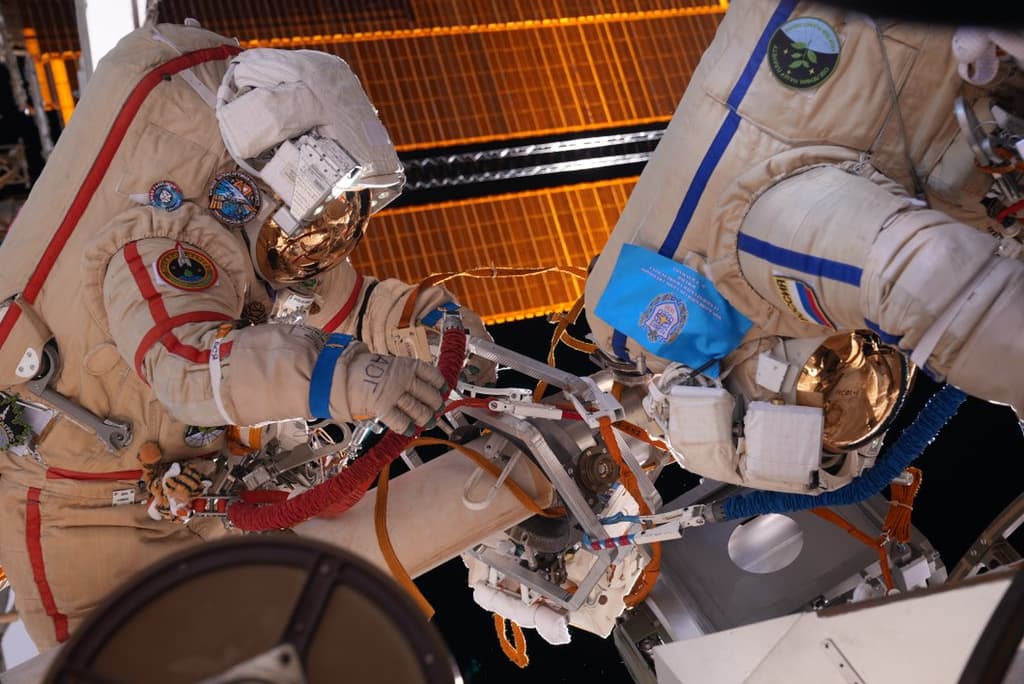 Los dos cosmonautas en pleno trabajo durante su paseo espacial; Artemyev está a la izquierda y Matveev, cabeza abajo, a la derecha; al fondo se ven los paneles solares de Nauka