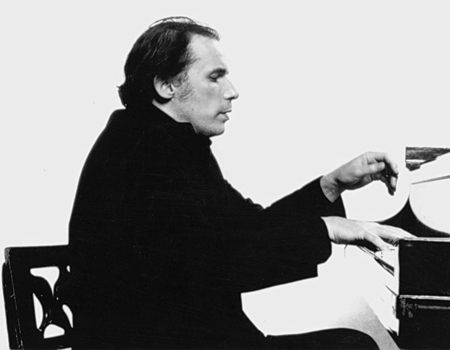 Foto en blanco y negro de Glenn Gould tocando el piano. A él se le ve sentado en una silla de cintura para arriba, con las manos levantadas sobre el teclado; del piano apenas se ve el teclado