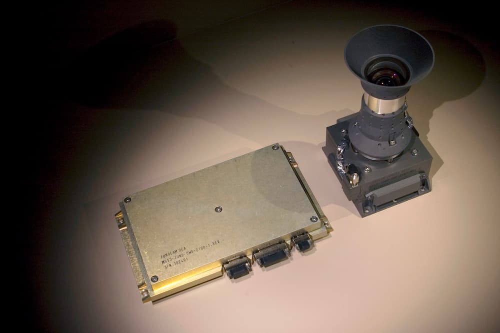 La cámara, a la derecha de la foto, con el objetivo apuntando hacia arriba, al lado de una delgada caja metálica rectangular que contiene su electrónica de control