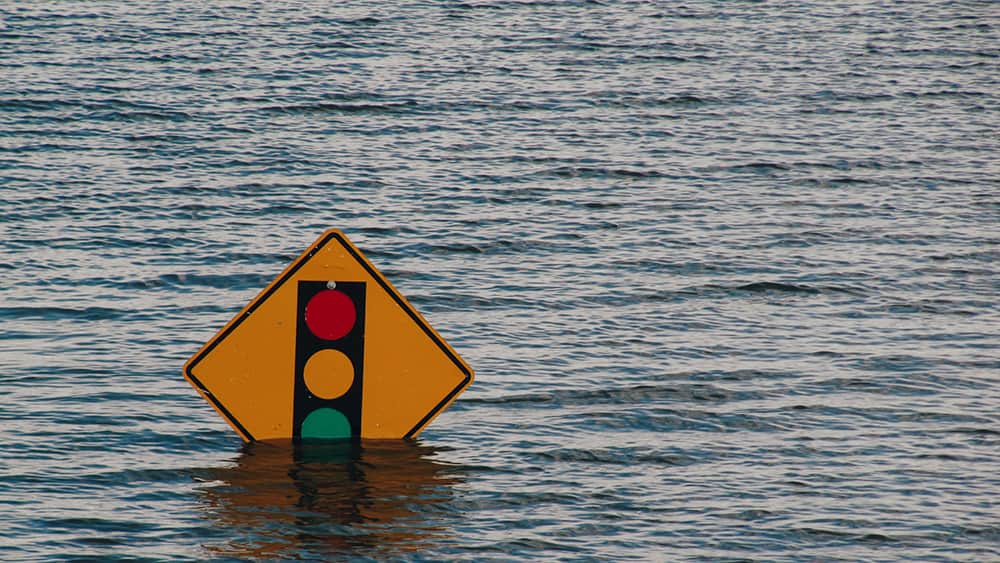 Una señal de tráfico que indica la proximidad de un semáforo a la que le llega el agua a la parte inferior