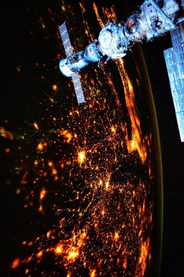 La Soyuz MS-21 acoplada al móduo Prichal de la EEI con la Tierra a la noche, aunque con abundante iluminación artificial, como fondo