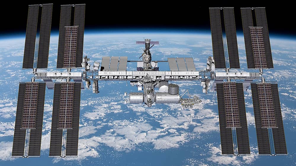 Impresión artística de la Estación en órbita vista desde arriba con la Tierra al fondo