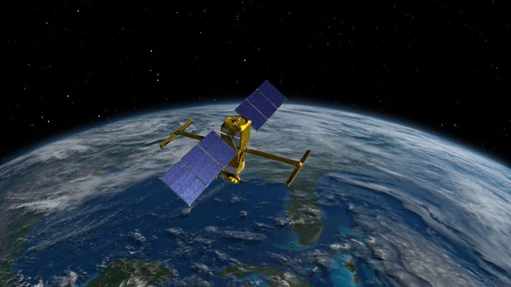 El satélite en órbita sobre la Tierra, que ocupa la parte inferior de la imagen, con sus antenas apuntando hacia ella