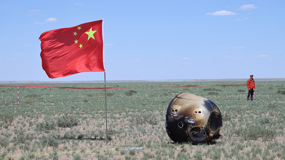 La cápsula de muestras posada de lado con una bandera china al lado