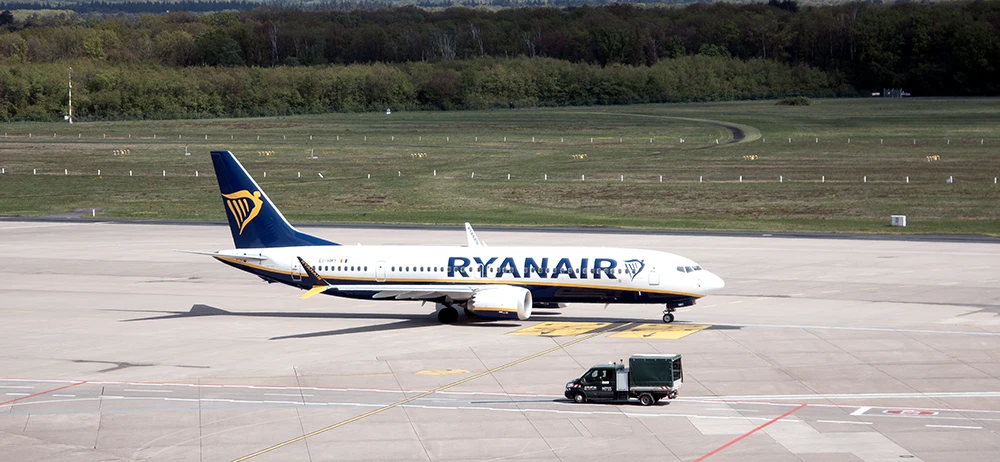 La foto procesada en Photoshop se le un 737 MAX de Ryanair desde un punto de vista elevado rodando por la plataforma del aeropuerto de Colonia; a su lado, en sentido contrario, pasa un camión