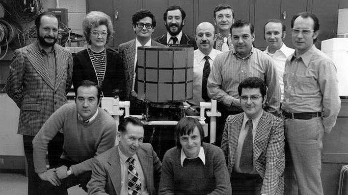 Un grupo de personas rodean un modelo del satélite en una foto en blanco y negro