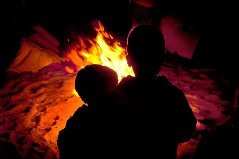 Dos niños a contraluz frente a una hoguera