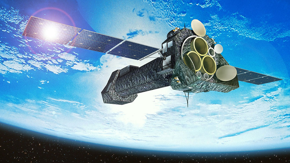 El XMM-Newton en el espacio con la Tierra al fondo y la luz del Sol reflejándose en sus paneles solares