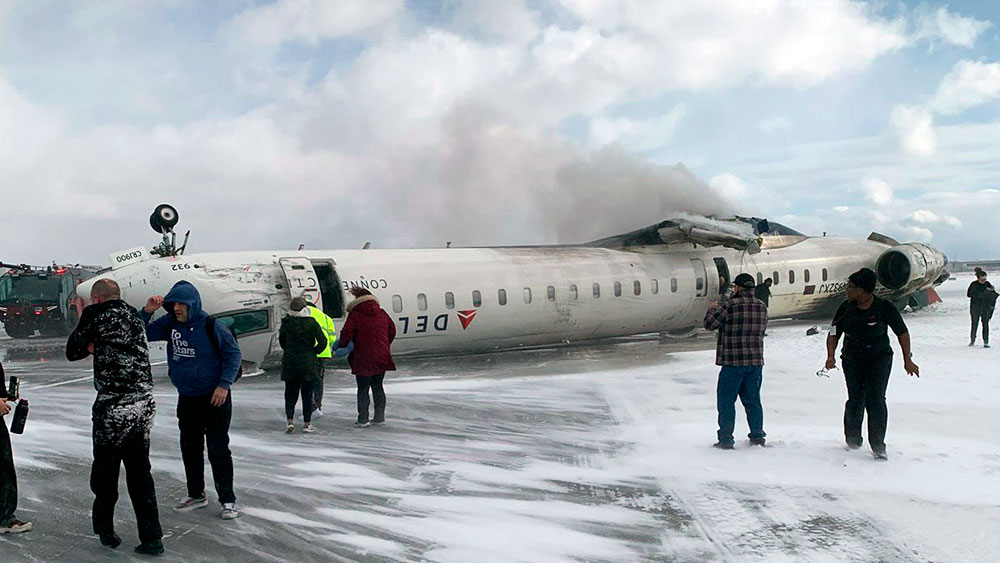 El avión destrozado sobre la pista visto desde la derecha, con parte del pasaje aún en el encuadre