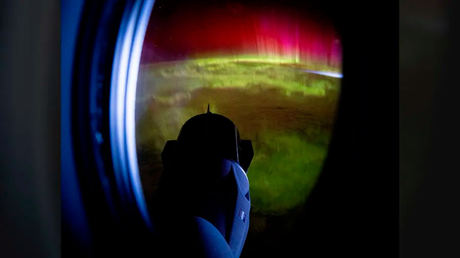 La Fredom vista a través de la ventanilla de la Endeavour con la Tierra con una aurora boreal como fondo