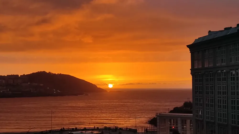 El Sol a piunto de ponerse en un atardecer anaranjado en A Coruña