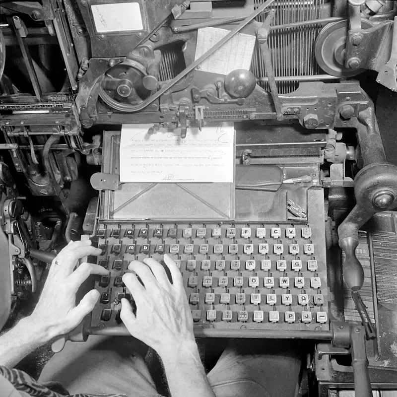 El teclado de una linotipia visto desde arriba con unas manos para darle escala